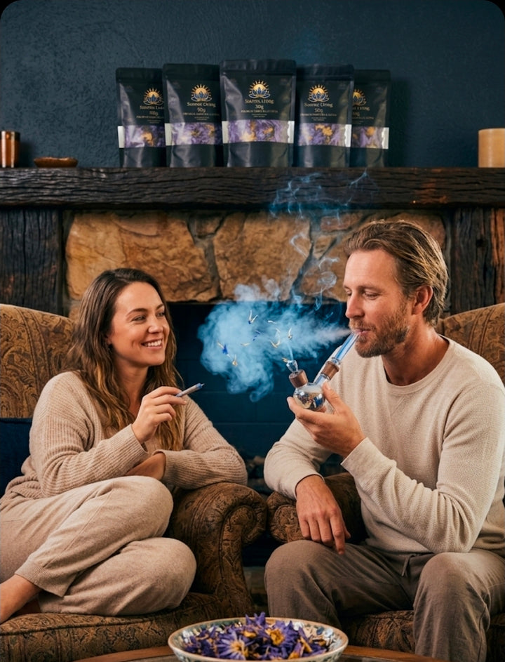 Two people sitting on a couch with a bowl of flowers and packages of tea in the background.
